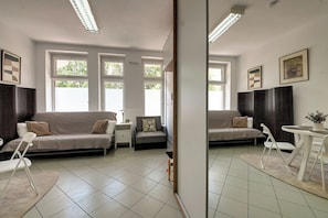 A modern living room with a sofa, chairs, a small table, and a mirror. - RentPlanet - Apartamenty Dawida (Wrocław)