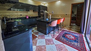 A modern kitchen with a central island, bar stools, and a patterned rug. - Perfect 2-bedroom Villa with Pool in delightful Ourika (Ourika)