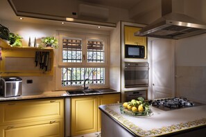 Una cucina moderna con piano cottura a gas, forno integrato, microonde e una finestra con grate decorative in ferro.