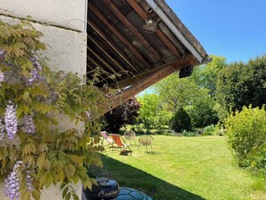 Ein Garten mit Grill, Gartenmöbeln und einer Pergola.