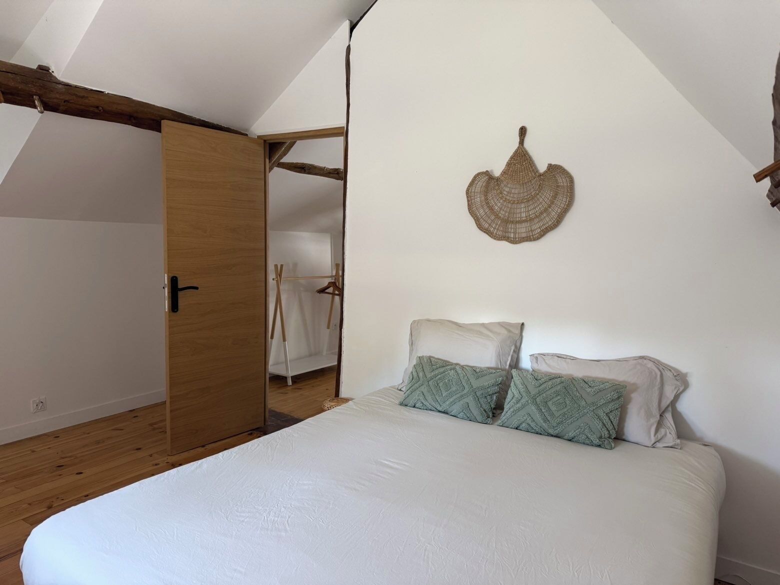 Un dormitorio con cama, una puerta de madera y un adorno en la pared.