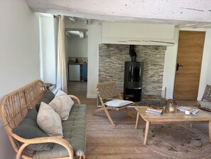 Ein Wohnzimmer mit Sofa, Couchtisch, Kamin und einer Küche im Hintergrund.