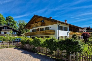 Ein traditionelles Chalet mit Holzbalkon, gepflasterter Auffahrt und Holzzaun.