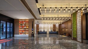 A modern lobby with a reception desk, a large bookshelf, and a green vertical garden. - Hampton by Hilton Huzhou Deqing (Huzhou)