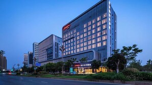 A modern hotel with a prominent 'Hampton' sign, large windows, and a well-lit facade. - Hampton by Hilton Huzhou Deqing (Huzhou)