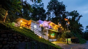 Un hotel moderno con fachada de piedra, varios balcones y un letrero de neón.