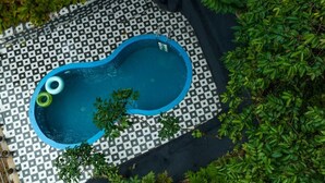 Una piscina pequeña y rectangular con un diseño de mosaicos en tablero de ajedrez a su alrededor.