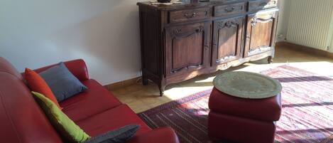 A living room with a red sofa, a wooden cabinet, and a patterned rug.