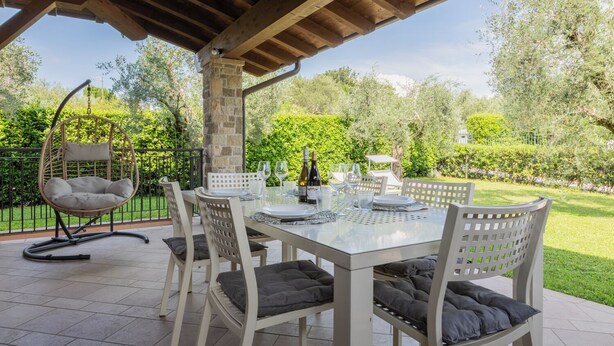 An outdoor patio with a table set for dining, surrounded by chairs with cushions. - CASA SAN GIORGIO, Family Apartment (Solarolo)