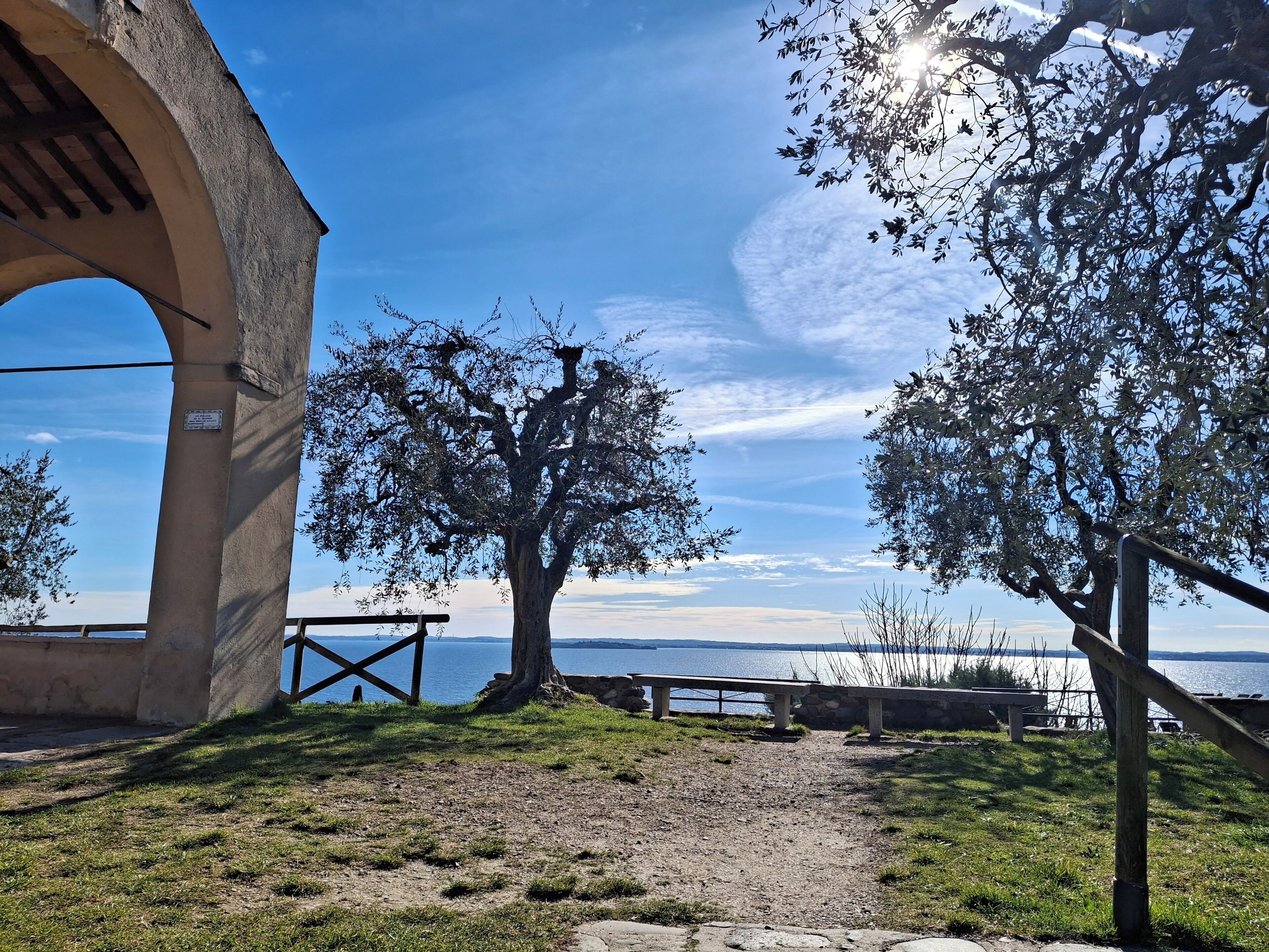 A pathway leading to a bench area with a view of the water and a stone structure.
