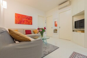 A modern living room with a sofa, a glass coffee table, and a painting on the wall. - CASA SAN GIORGIO, Family Apartment (Solarolo)