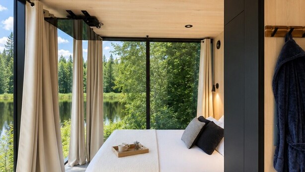 A bedroom with a bed, a tray with a cup and a glass, and a view of a lake and trees.