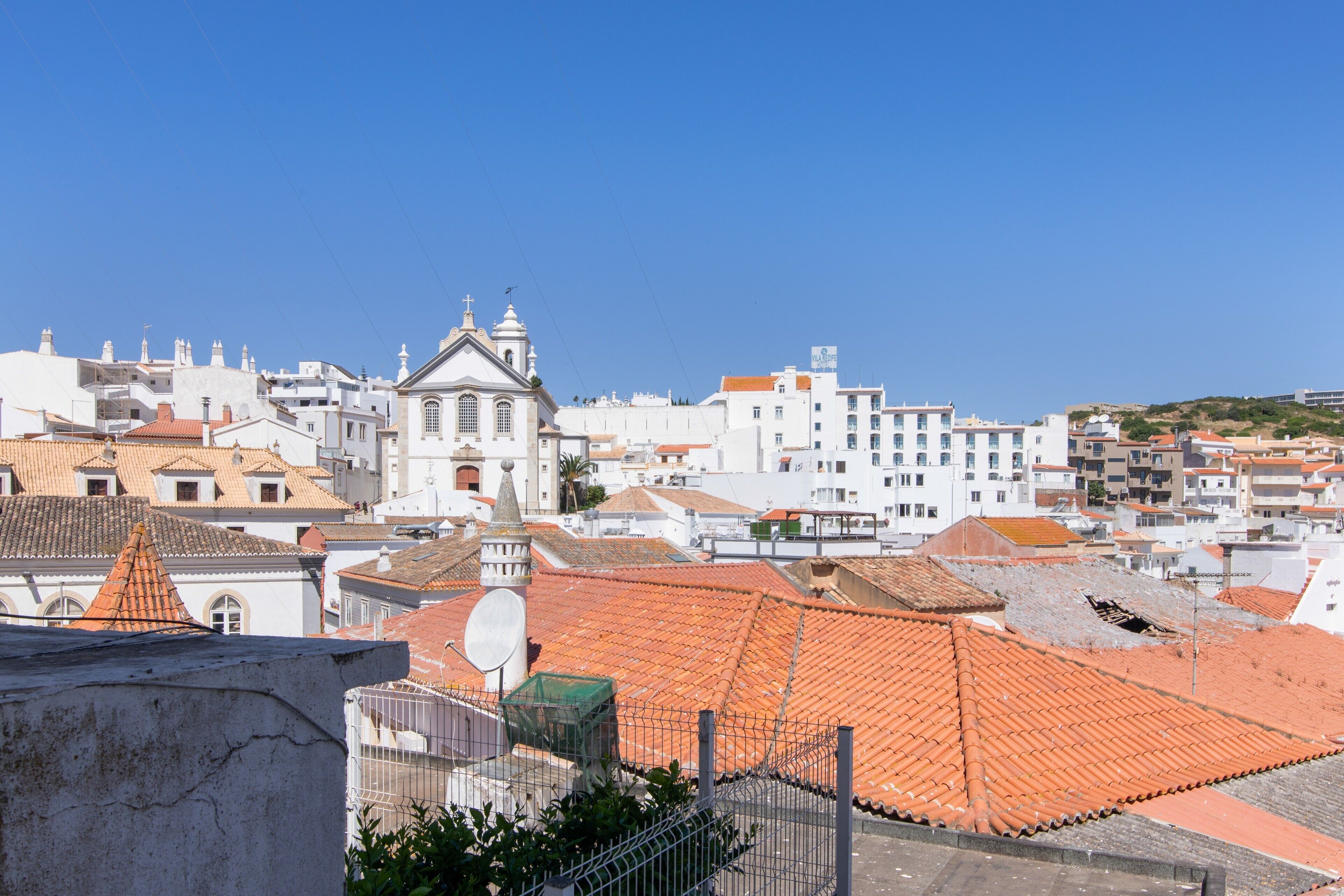 Un paisaje urbano con una iglesia destacada, edificios blancos y tejados de tejas rojas.