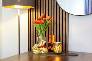 A wooden table with a lamp, a vase of red tulips, two bottles of champagne, and two chocolate bunnies. - Design-FeWo at the Möhnesee with unique lake view, balcony, pool, sauna, elevator (Möhnesee)