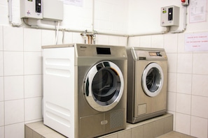 A laundry facility with two washing machines, a control panel, and a sign in German.