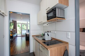 A modern kitchen with a built-in microwave, a coffee maker, and a sink. - Design-FeWo at the Möhnesee with unique lake view, balcony, pool, sauna, elevator (Möhnesee)