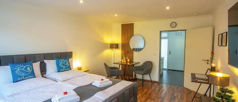 Een hotelkamer met een bed, nachtkastjes, een bureau, een stoel, een spiegel, een klok en een potplant.