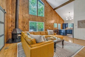Ein modernes Wohnzimmer mit einer großen Couch, einem Kamin und einer Küche im Hintergrund.