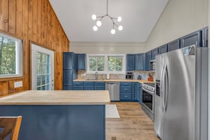 Eine moderne Küche mit Holzwänden, blauen Schränken, einem Edelstahlkühlschrank und einer zentralen Kochinsel.