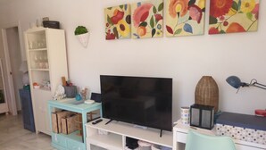 Un soggiorno con TV, scrivania, una sedia, una libreria e decorazioni alle pareti.