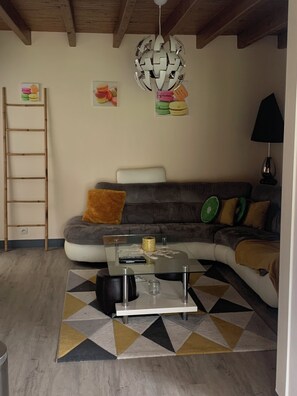 Ein Wohnzimmer mit einer Couch, einem Couchtisch, einer Leiter und einem Teppich mit geometrischem Muster.