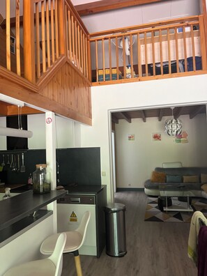 Eine moderne Küche mit einer Holztreppe, einem Essbereich mit einer Couch und einem Mülleimer.