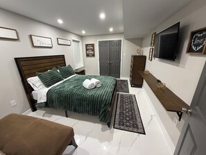 Ein Schlafzimmer mit Bett, Nachttisch, Bank, Kleiderschrank, Fernseher und motivierenden Wandbildern.