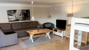 Ein Wohnzimmer mit einer Couch, einem Couchtisch, einem Fernseher und einem Etagenbett.