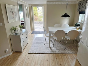 Ett modernt kök med matplats, vita köksskåp och en hängande taklampa.