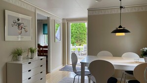 Ein Essbereich mit Tisch, Stühlen, einem Deckenventilator und einem gerahmten Kunstwerk an der Wand.