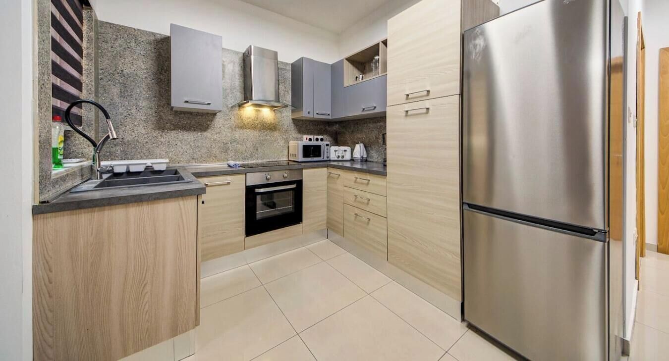 A modern kitchen with a stainless steel refrigerator, a microwave, and a built-in oven.