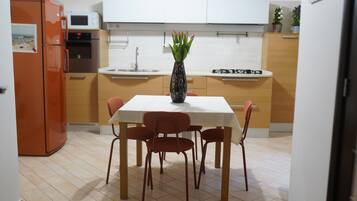 Una cocina moderna con una mesa de comedor, sillas, un jarrón con flores y un microondas.