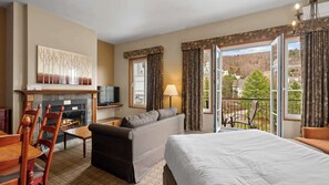 Ein Hotelzimmer mit Kamin, einer Couch, einem Bett, einem Fernseher und einem Balkon mit Blick.
