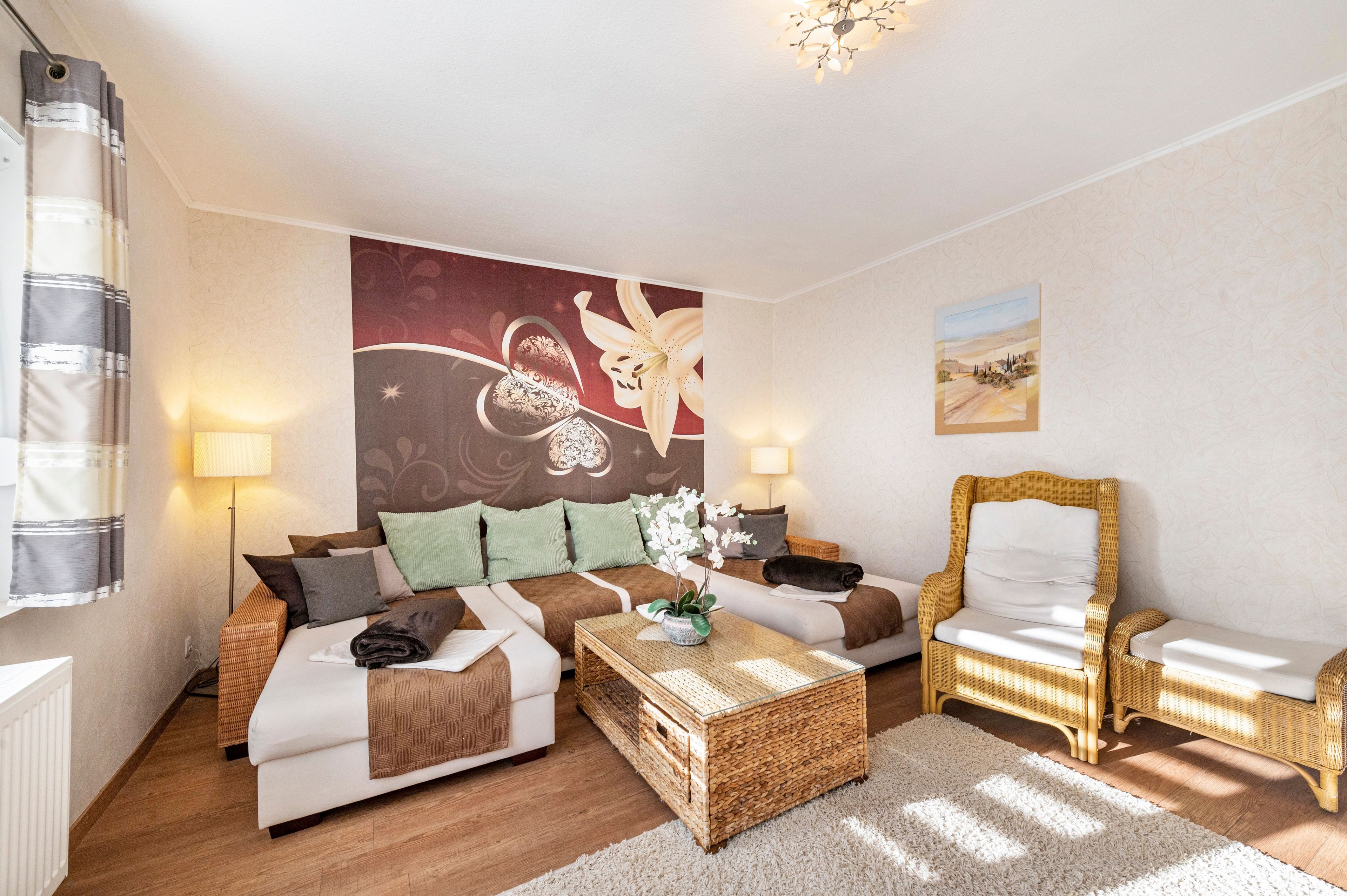 Une pièce bien éclairée, avec un canapé, un fauteuil, une table basse et un mur orné d’un tableau.