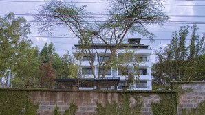Un immeuble à plusieurs étages portant une enseigne indiquant « MBUGAN WHITE HOUSE SUITES ».