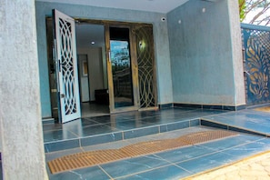 A building entrance with a sliding glass door, a tiled floor, and a decorative metal gate. - Mbugani View Suites (Ongata Rongai)