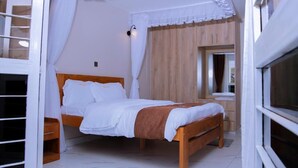 Une chambre à coucher avec un lit en bois, du linge de lit blanc, une table de chevet, une armoire en bois et une fenêtre avec des rideaux.