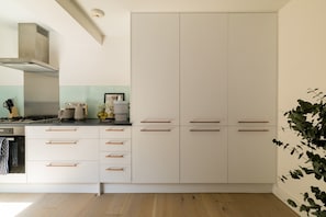 Eine moderne Küche mit weißen Schränken, Holzgriffen, einer Edelstahl-Dunstabzugshaube und einer Arbeitsplatte mit verschiedenen Geräten.