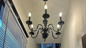 A staircase with wooden steps and a black railing, leading to a landing with a chandelier. - The Uptown Suite - Big Red, 1903; Downtown; 2 bedroom 1 full bath, 3 queen beds (Wilmington)