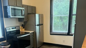 A compact kitchen with a built-in oven, microwave, and refrigerator. - The Uptown Suite - Big Red, 1903; Downtown; 2 bedroom 1 full bath, 3 queen beds (Wilmington)