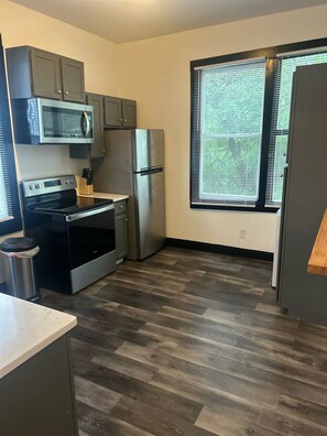 Una cocina compacta con horno integrado, microondas y refrigerador.