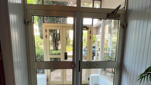 Blick durch eine Glastür in einen überdachten Außenbereich mit Fußmatte.