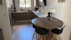 Eine moderne Küche mit Essbereich, einer Uhr an der Wand und einem 'HOME'-Schild.