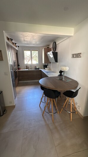 A modern kitchen with a dining area, a clock on the wall, and a 'HOME' sign. - Newly renovated apartment in the center of Saint Raphaël. (Saint-Raphaël)