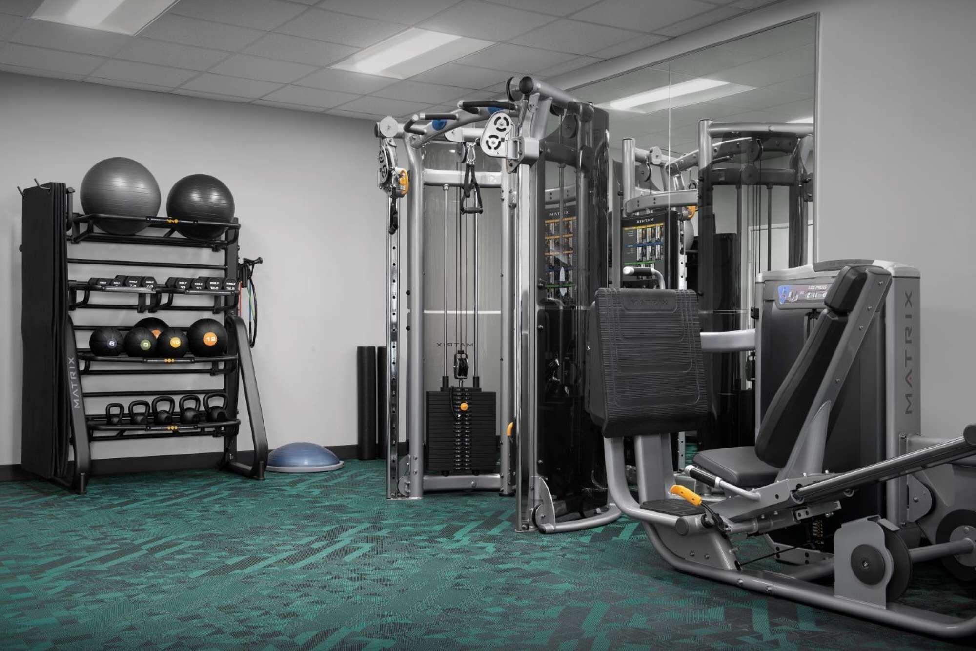 Een sportschool met gewichthefapparatuur, trainingsballen en een cardioapparaat.