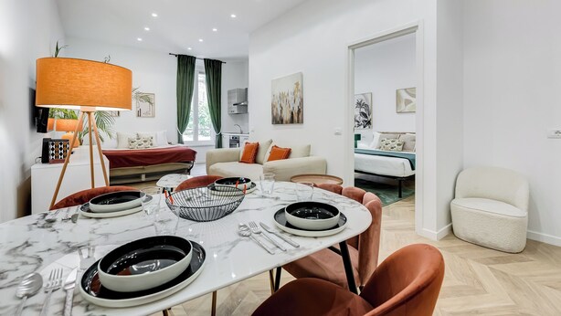 Ein modernes Wohnzimmer mit Essbereich, einer Couch, einem Fernseher und einem Bett.