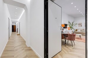 A modern interior with a hallway leading to a dining area, a sofa, and a plant. - Heart St Peter - Rome Dream Home (Roma)