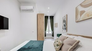 Ein modernes Hotelzimmer mit einem Bett, einem Fernseher, einer Klimaanlage, einem Fenster mit Vorhängen und Kunstwerken an den Wänden.