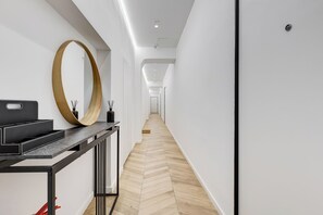 A hallway with a herringbone floor, a black console table with a mirror, and a door at the end. - Heart St Peter - Rome Dream Home (Roma)