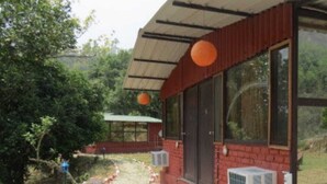 Un bâtiment à la façade en briques rouges, doté de grandes fenêtres et d’un porche abrité.